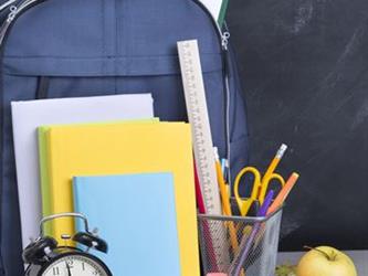A variety of school supplies next to a backpack