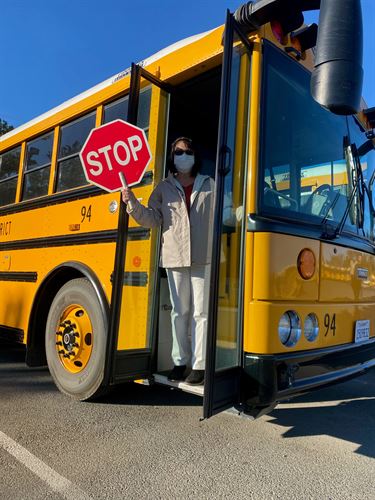 A bus driver standing in the doorway of a school bus
